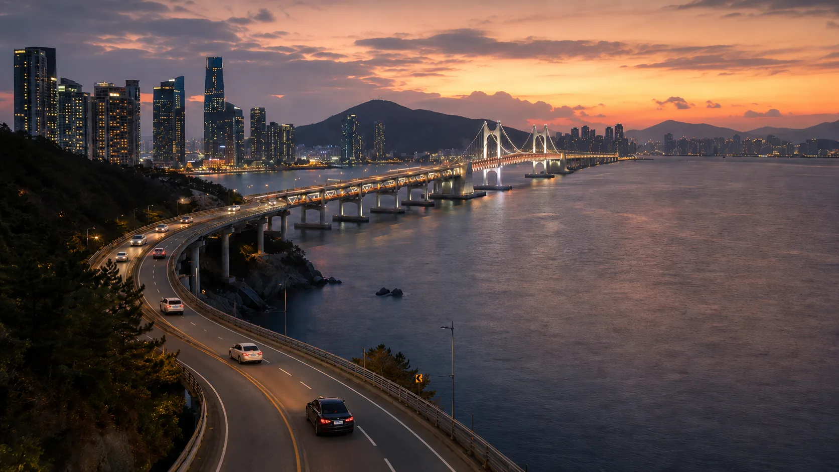 Black Genesis G90 sedan on Busan's coastal expressway near Gwangan Bridge at warm dusk — Korea chauffeur service